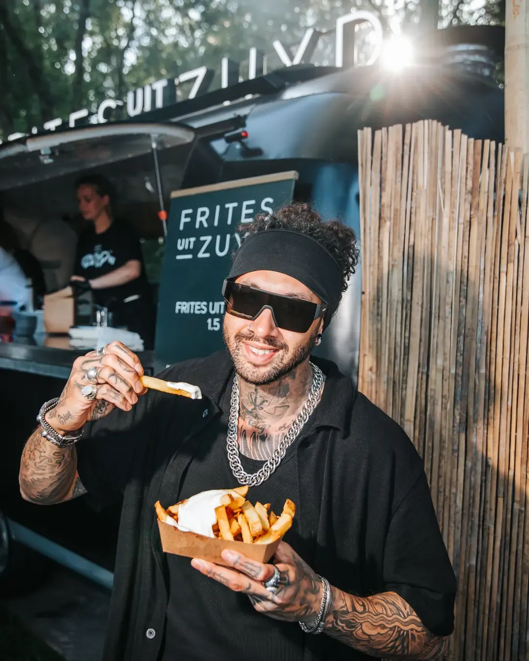 Festivalbezoeker met een bakje frites bij de Airstream