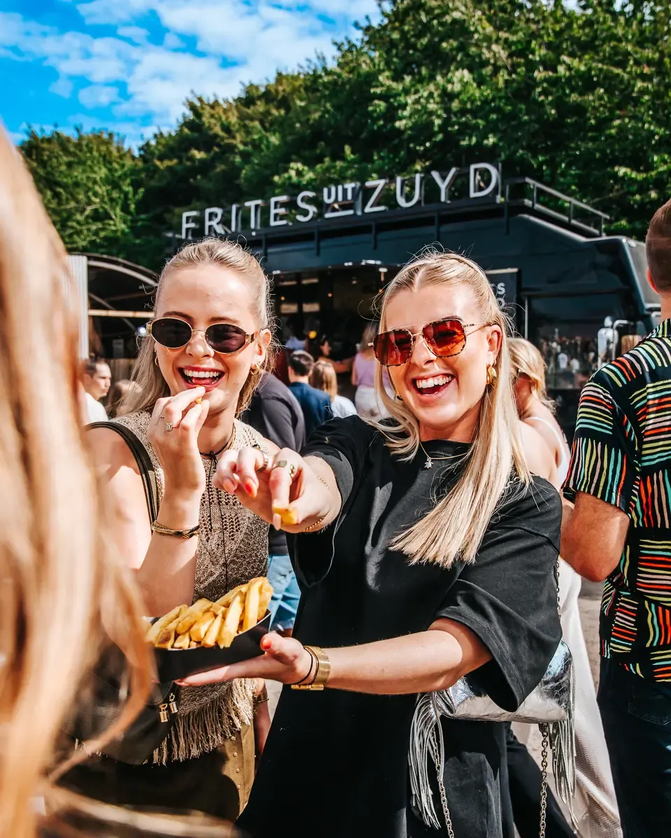 Twee bezoekers met frites voor de foodtruck van Frites uit Zuyd